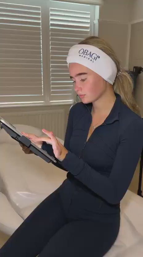 Client completing her skin consultation form on a tablet in clinic